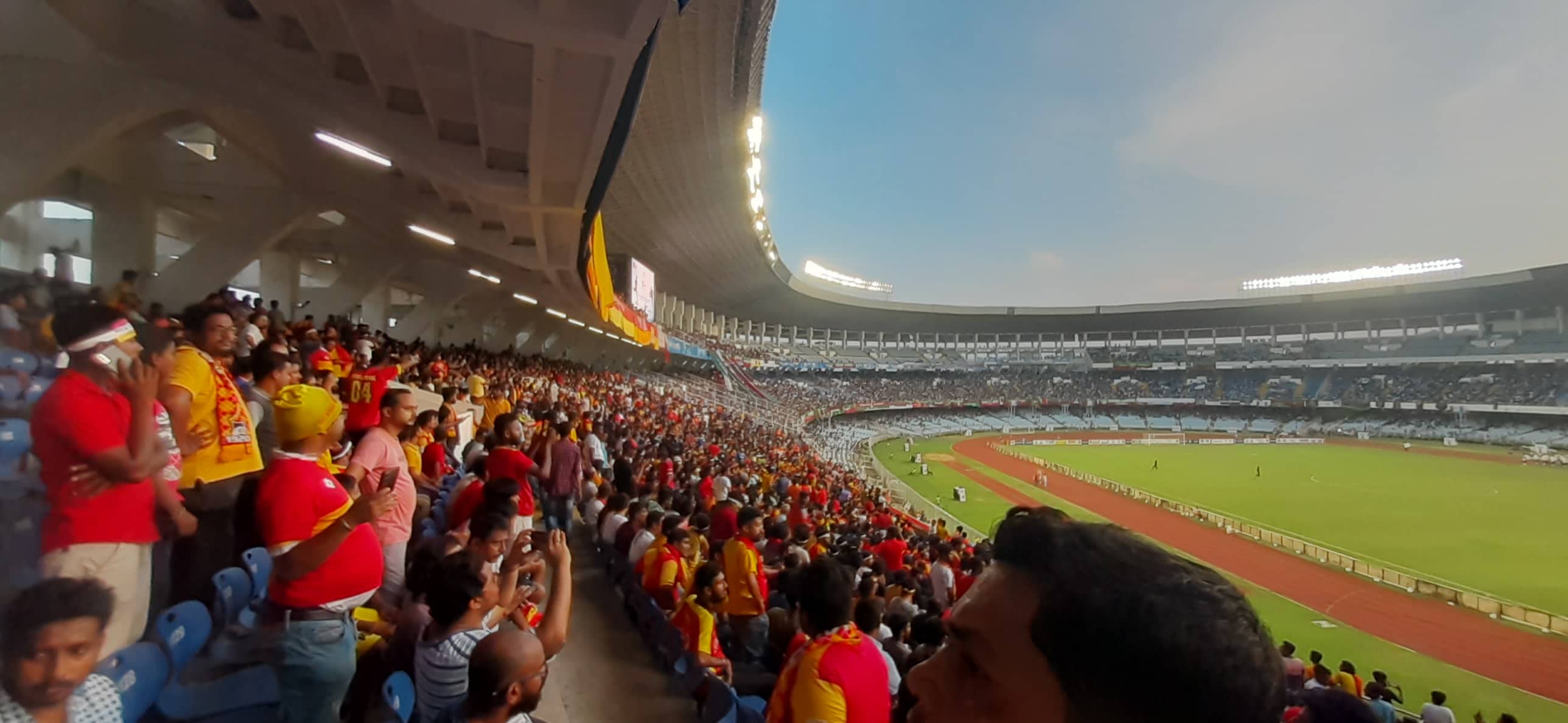 Indian football supporters in Kolkata checking match timing around a live football event.