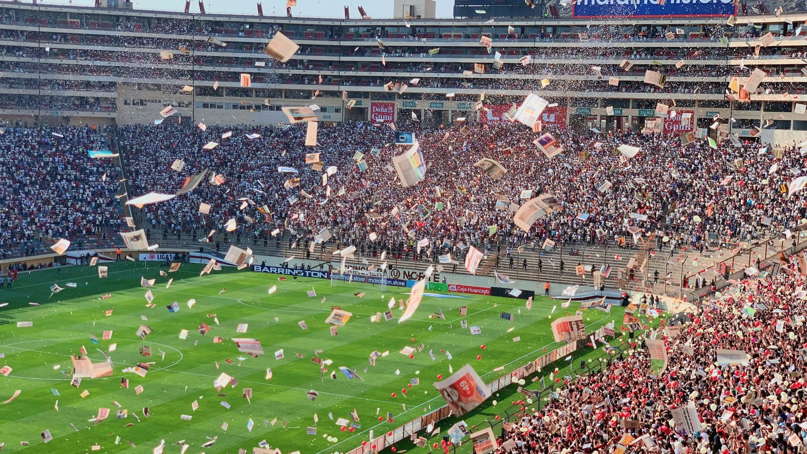 Packed football stadium with fans and paper flying before a major match.